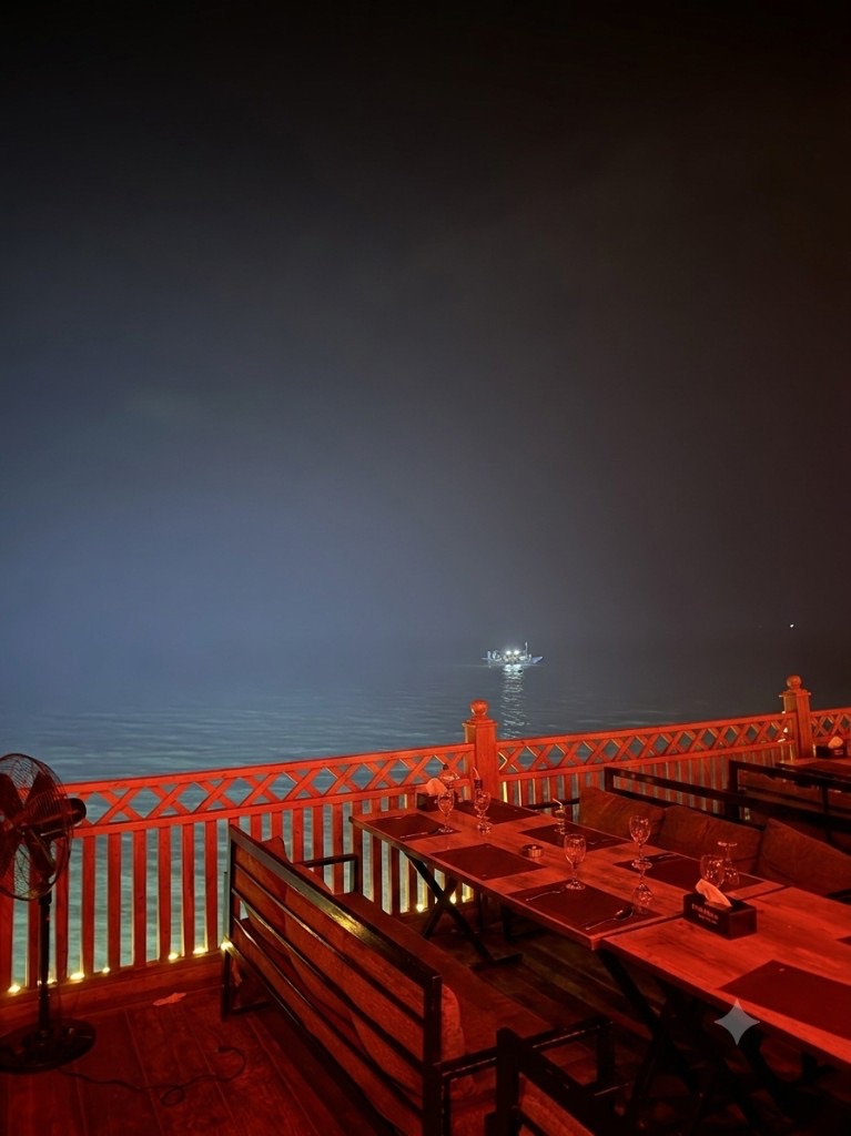 A red-lit waterfront restaurant overlooking calm water at night