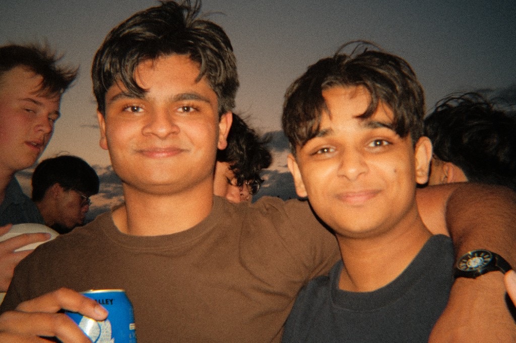 Two friends with their arms around each other at an outdoor gathering