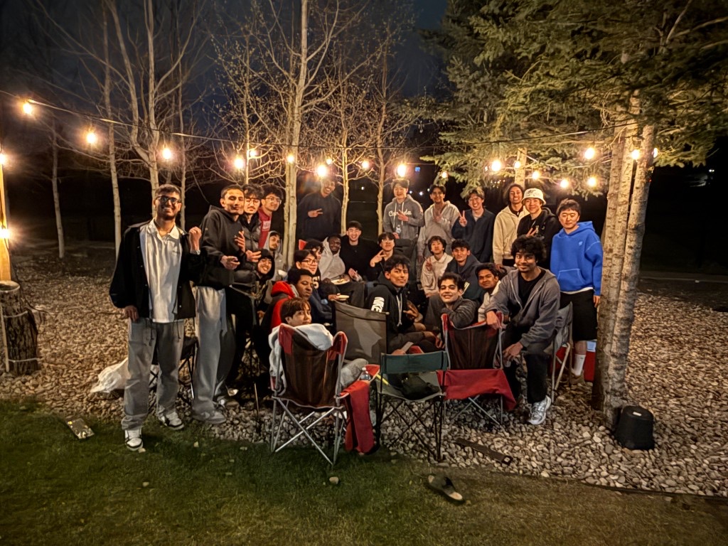 A large group of friends gathered outdoors under string lights