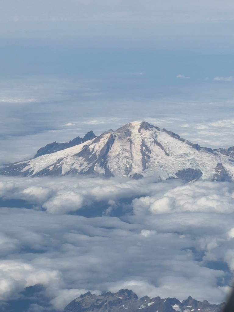 A snow-covered mountain rising above a blanket of clouds