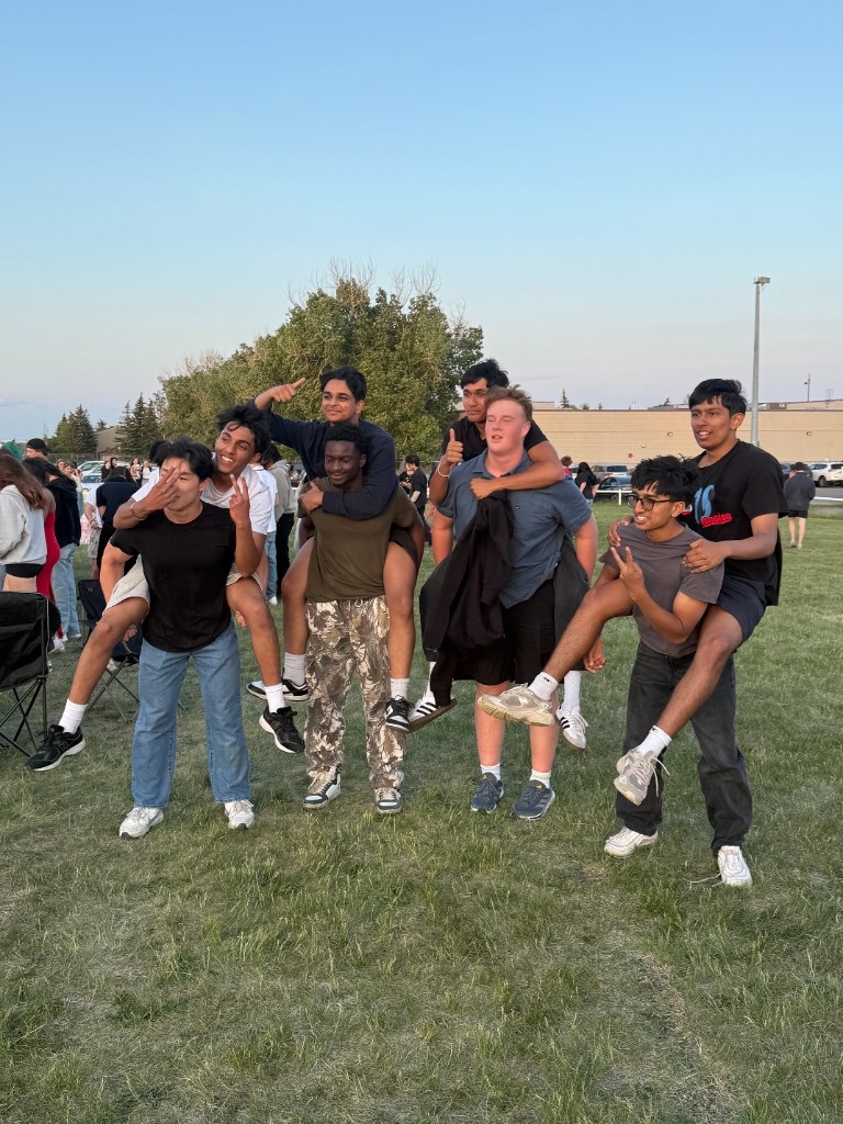 Friends laughing and giving each other piggyback rides in a field