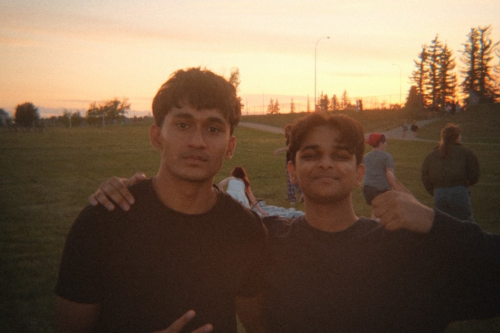 Ali and a friend standing together in a park during sunset