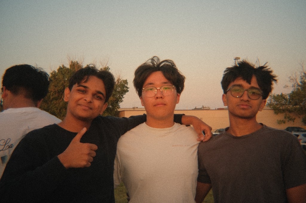 Three friends posing together outdoors in a warm film-style photograph