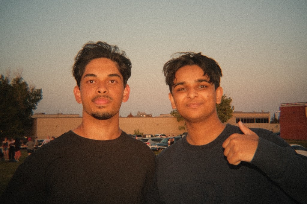 Ali giving a thumbs up beside a friend at an outdoor gathering